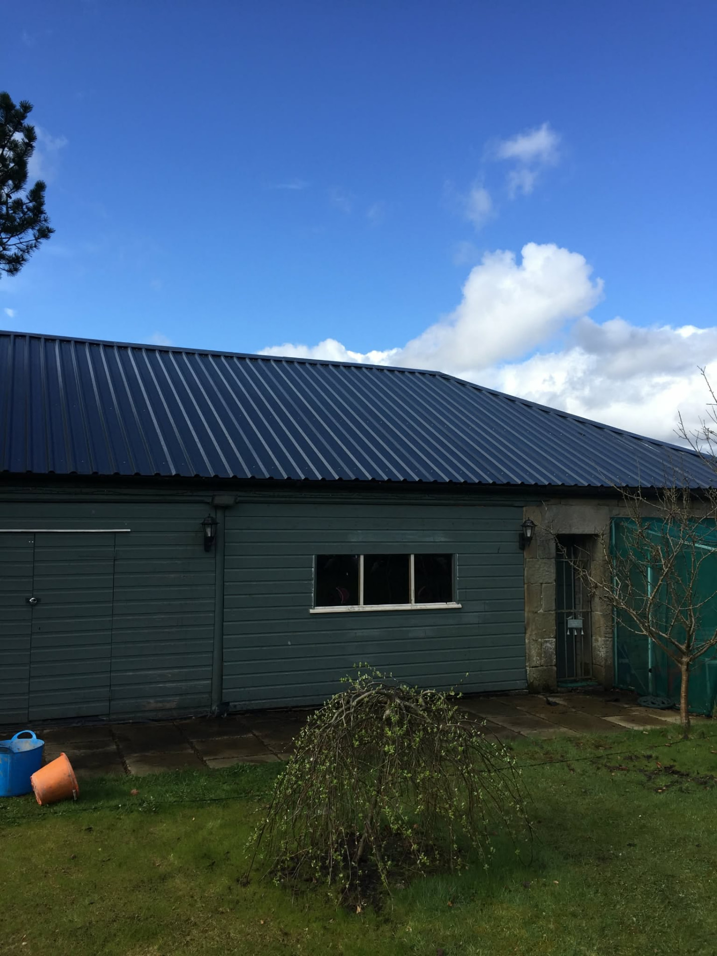 Dark box-profile metal roof fitted to an outbuilding